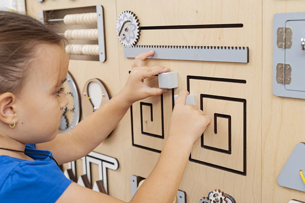 Child exploring a sensory wall for autism and ADHD, developing focus and calm through inclusive, hands-on play with BumblebeeSmart sensory panels.